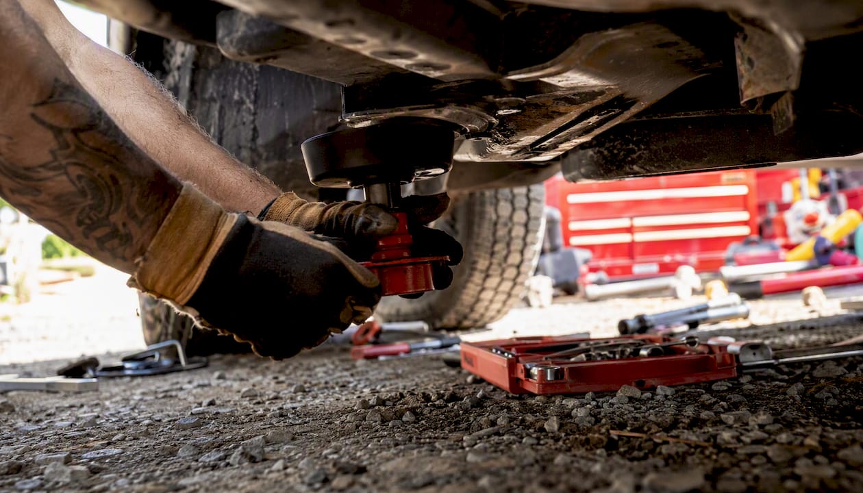 Hands attaching portable underbody lift to car chassis
