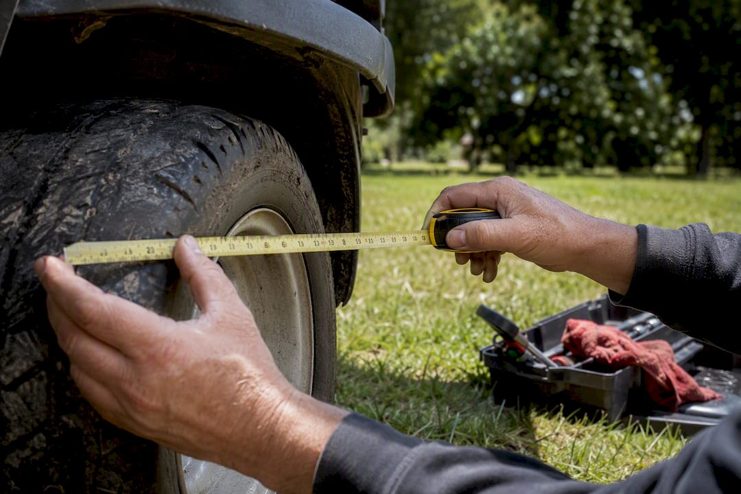 Close-up of hands measuring golf cart tire diameter