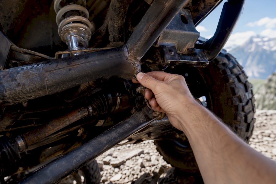 Hands inspecting ATV suspension and frame details