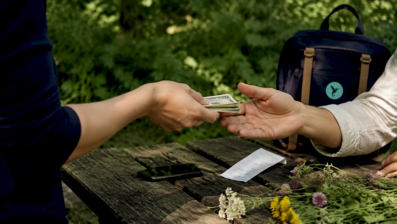 How Group Expense Tracking Works For Shared Costs 2 Hands exchanging payment to settle expenses
