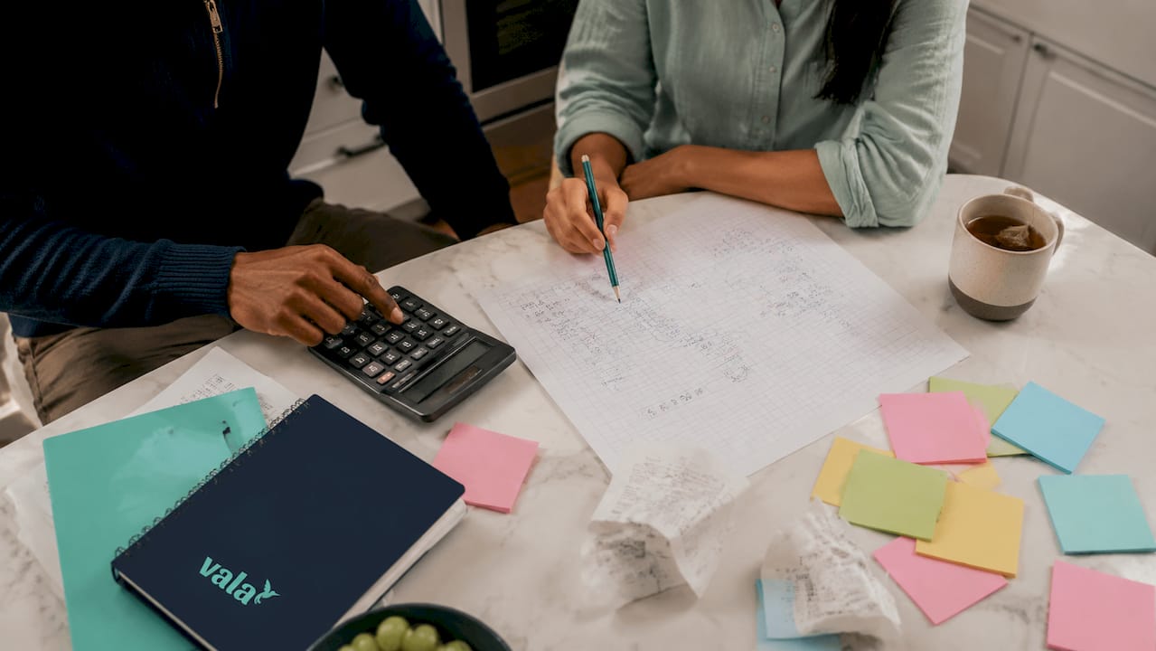 What Is A Shared Budget? Methods, Tips, And Tools 2 Hands calculating shared budget with calculator and notes
