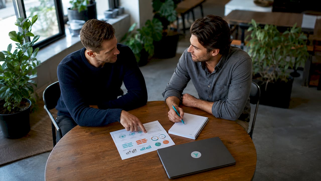 Types Of Savings Goals By Age: Your Decade-By-Decade Plan 7 Two men discussing age-specific savings goals in office