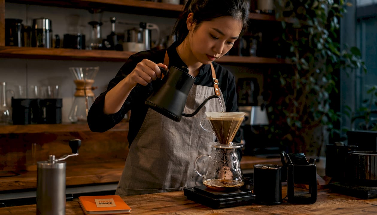 Barista hand-pouring water during manual pour over coffee brewing