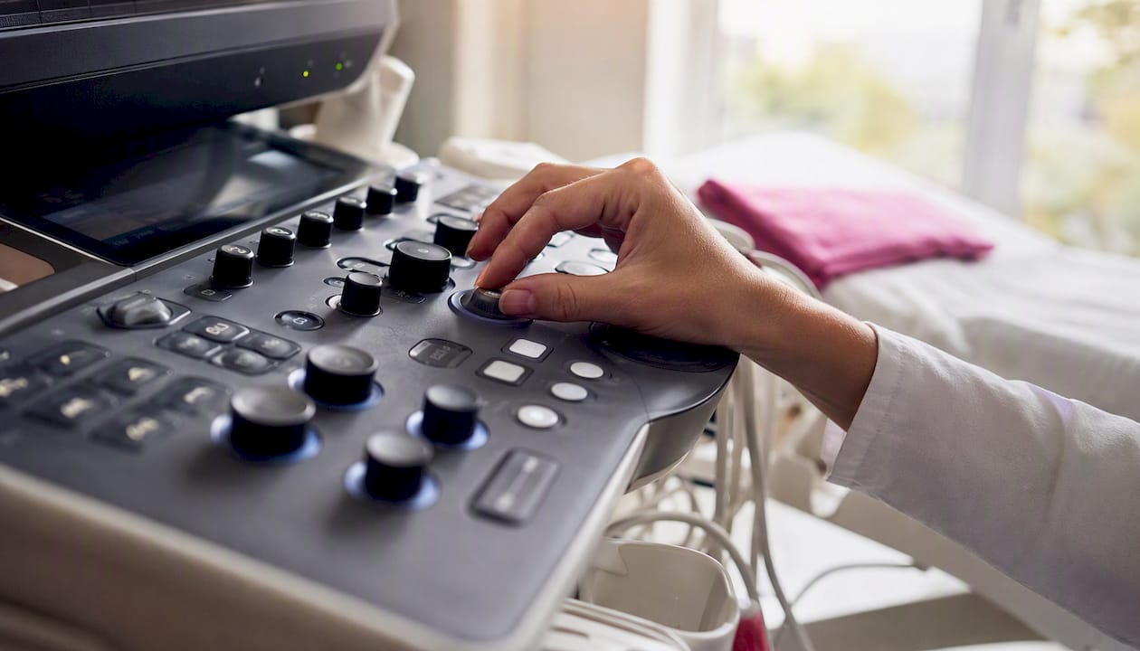 Una mano ajustando el panel de un equipo de ultrasonido.