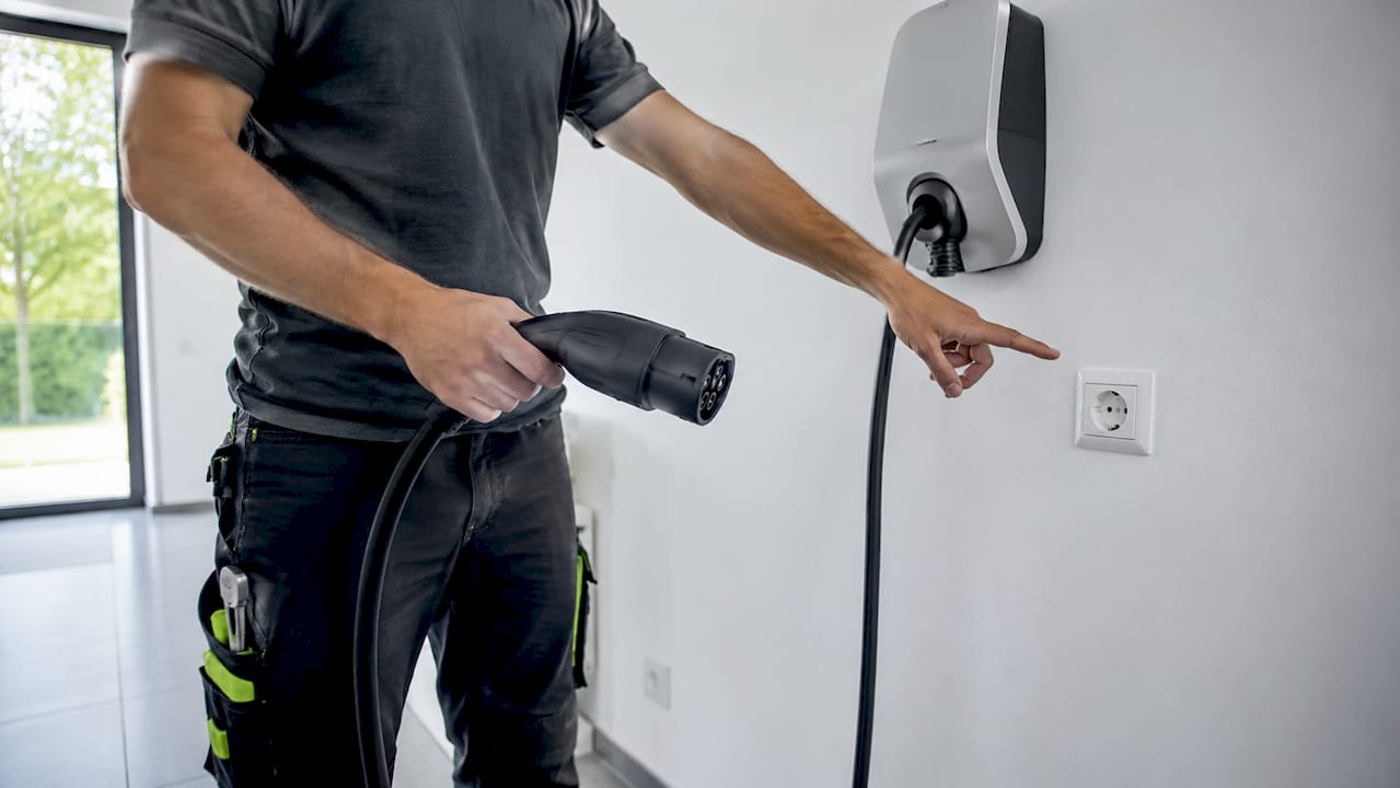Ein Elektrotechniker zeigt die Unterschiede zwischen einer Wallbox und einer herkömmlichen Steckdose auf.