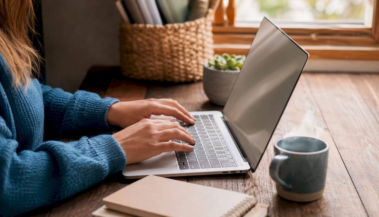 Hands typing at laptop in coworking space