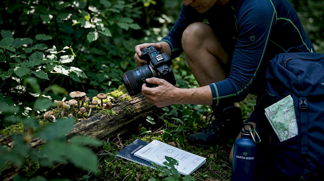 Photographer adjusting camera in forest setting