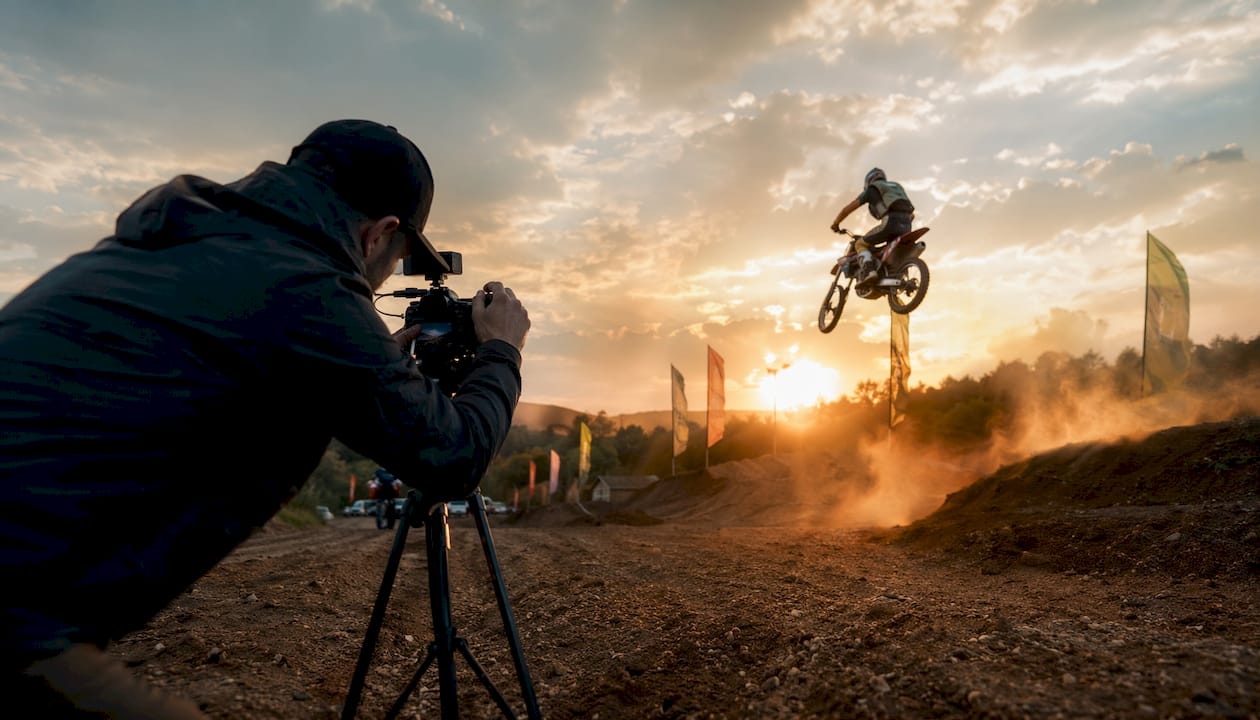 Camera operator filming motocross with professional lighting