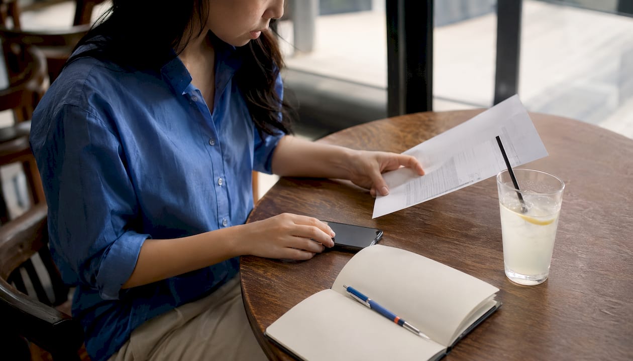 Hands verifying wire transfer instructions at office desk