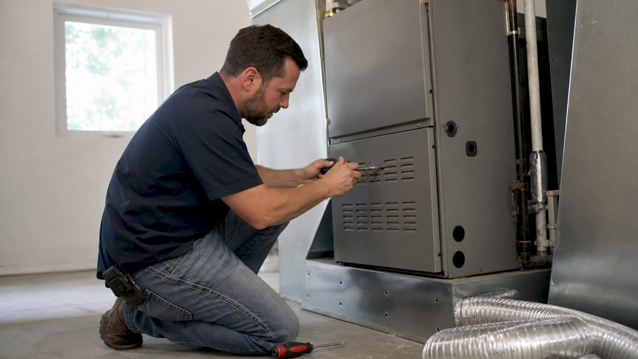 HVAC technician installing gas furnace in basement