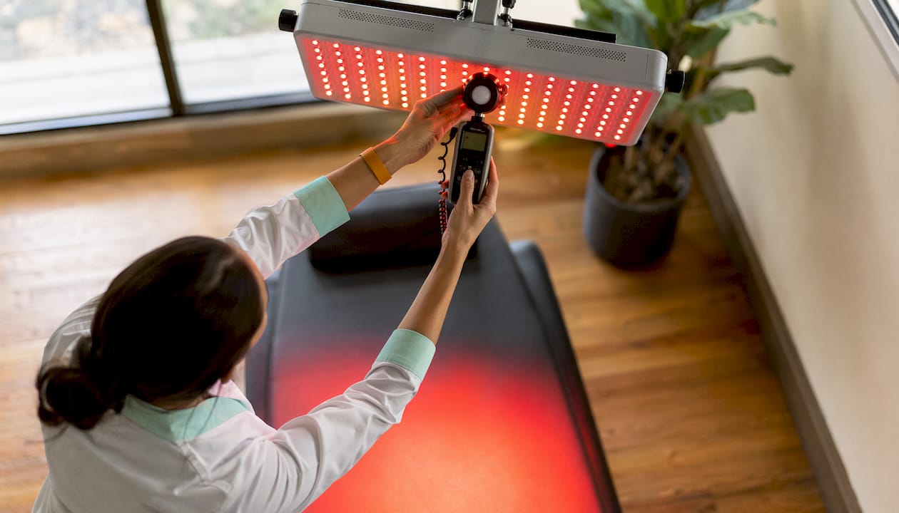 Technician measuring red light irradiance in clinic