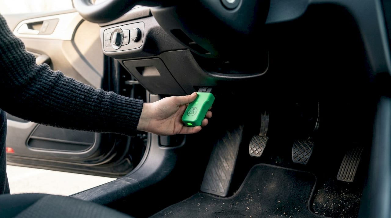 Hand inserting OBD2 power adapter in car port