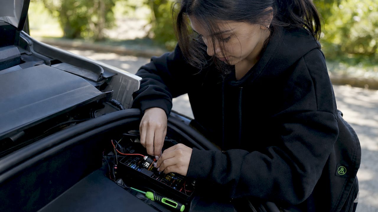 Hands wiring dashcam in electric vehicle fuse box