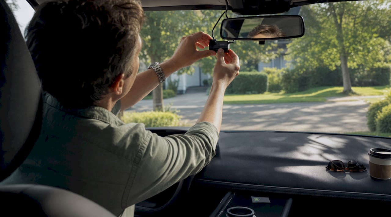 Person adjusting dashcam in driveway