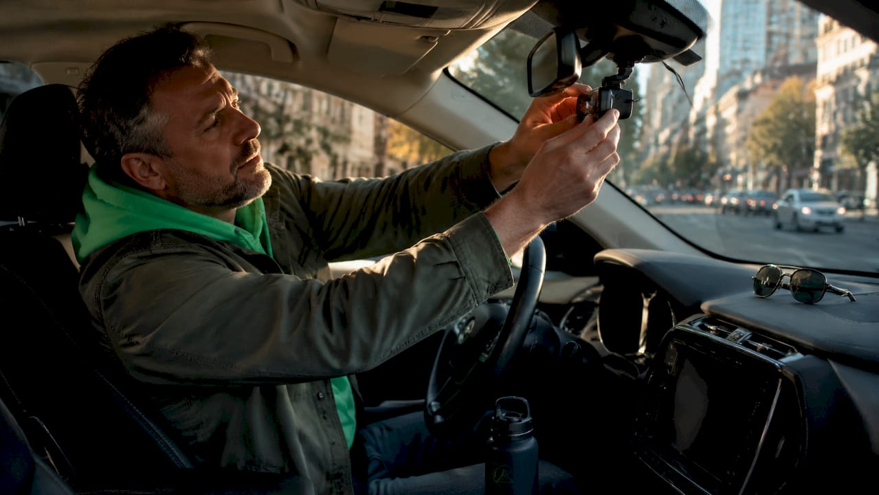Driver adjusting dashcam inside car