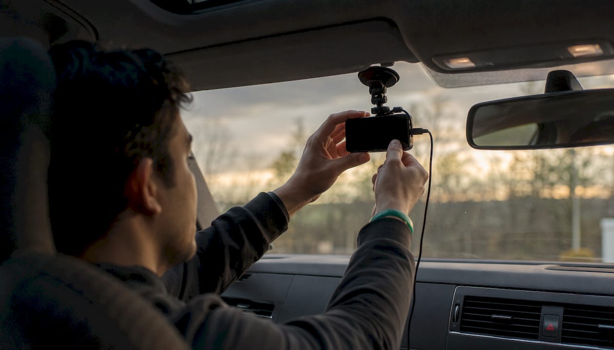 Hands securing dashcam mount on windshield