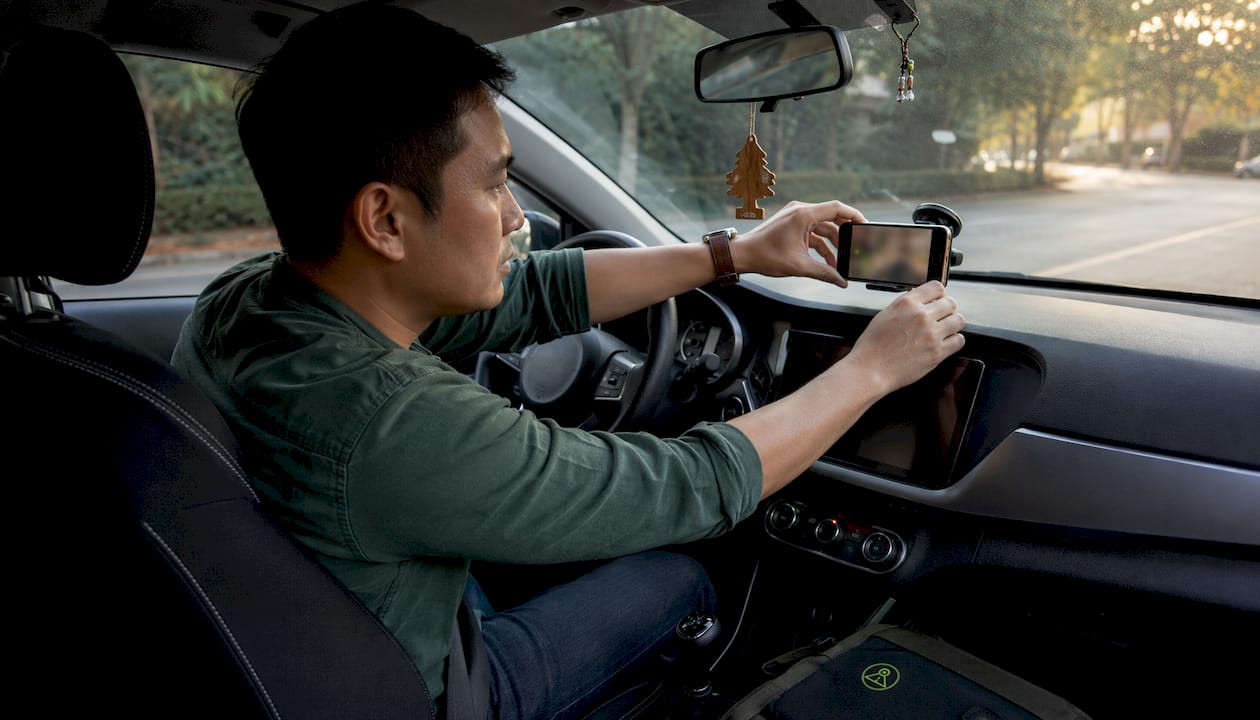 Driver adjusting smartphone dashcam in car