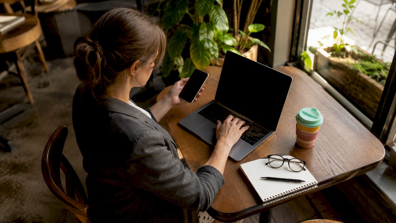 Woman using laptop and smartphone at coworking desk