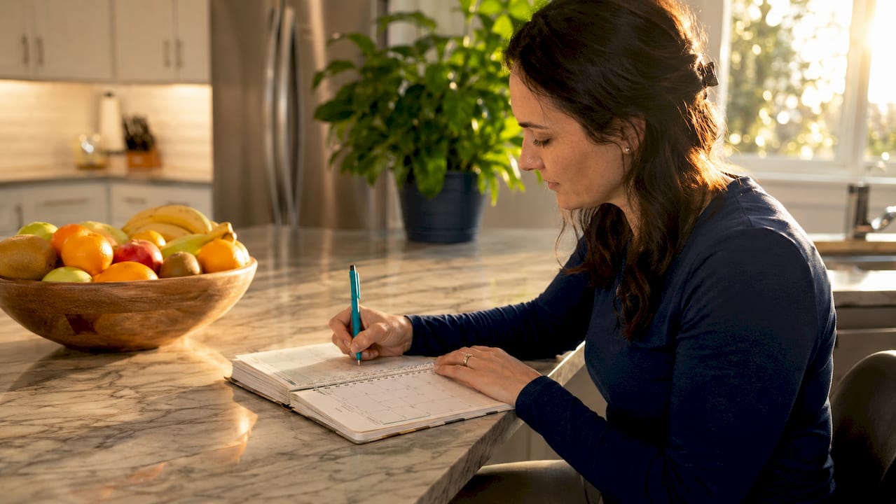 Hands writing spinal health goals in planner