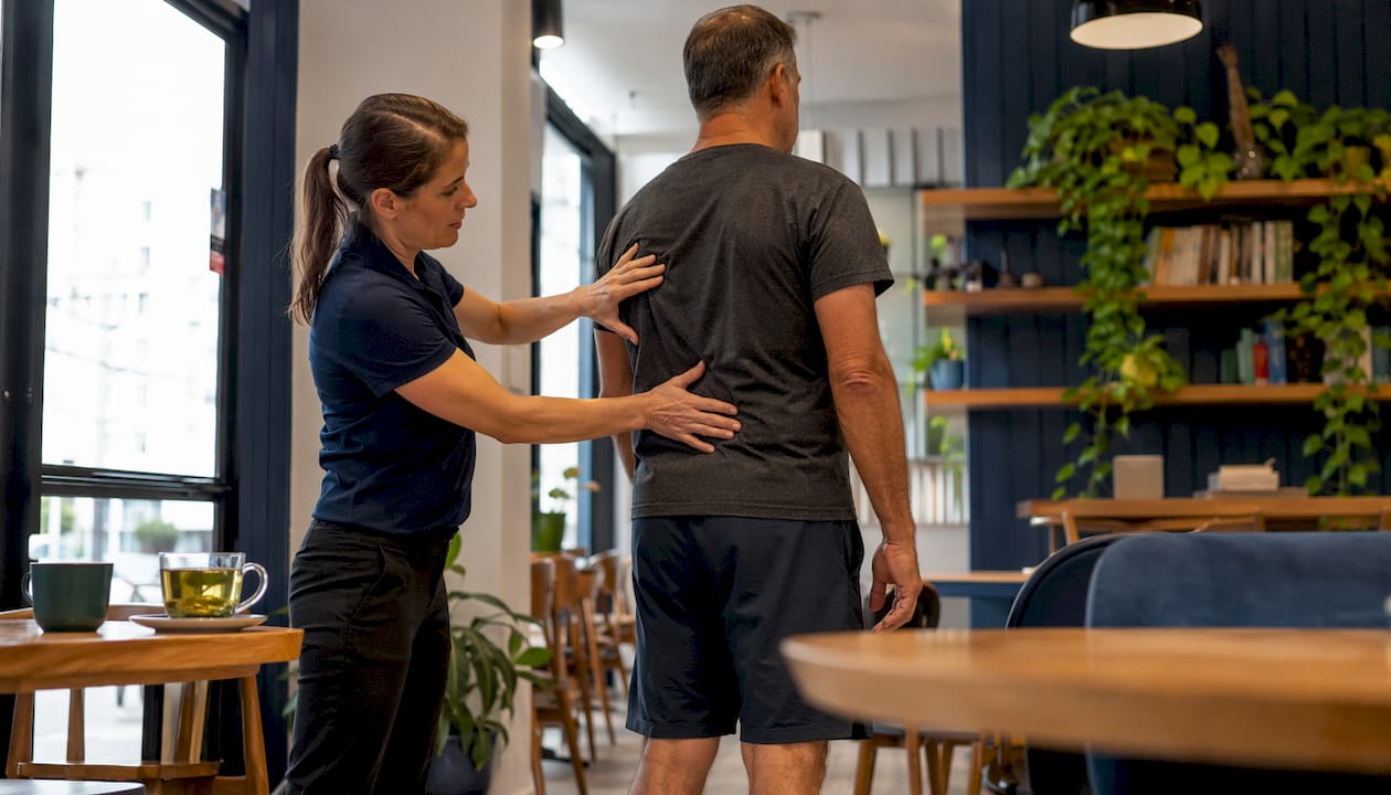 Chiropractor assessing patient's posture in clinic