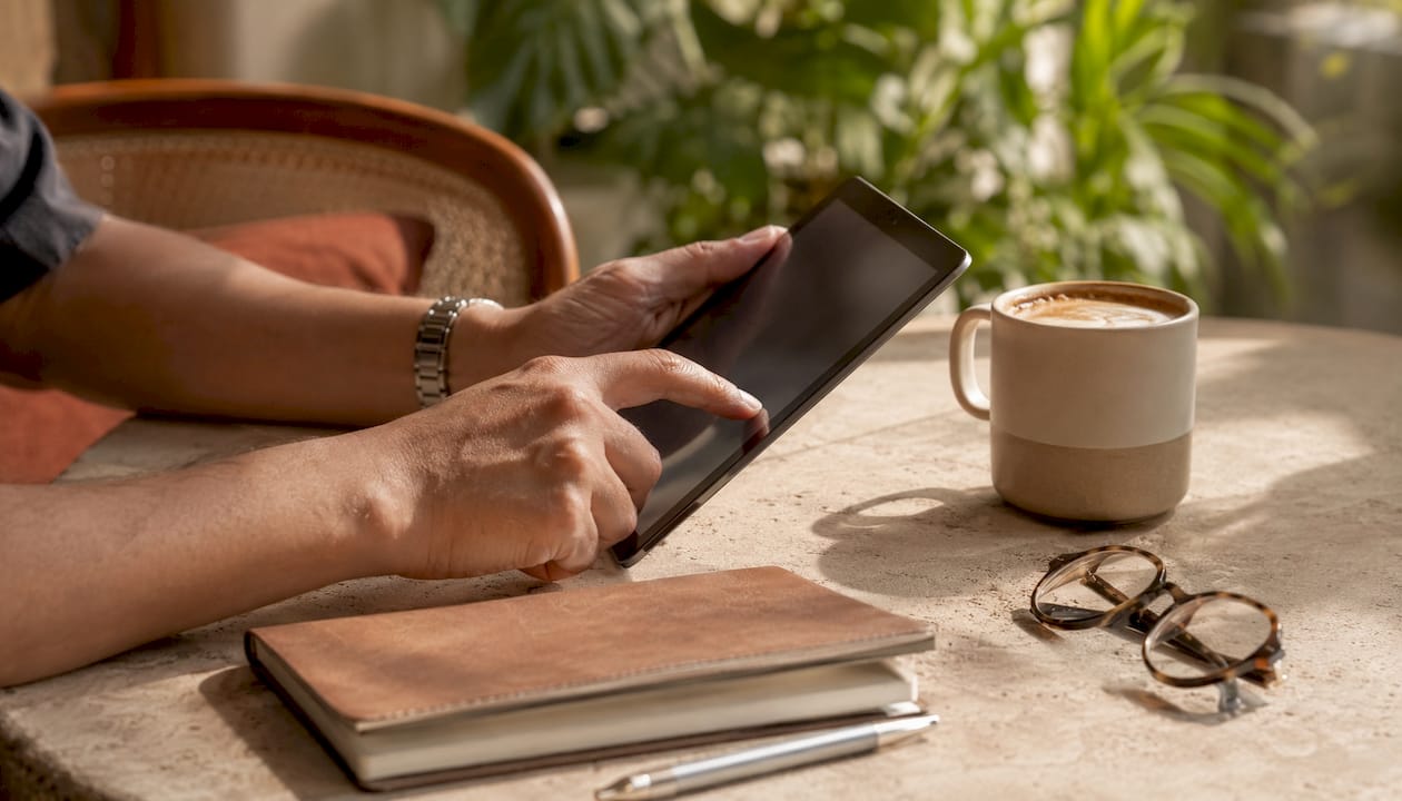 Hands scrolling tablet in cafe reviewing platforms