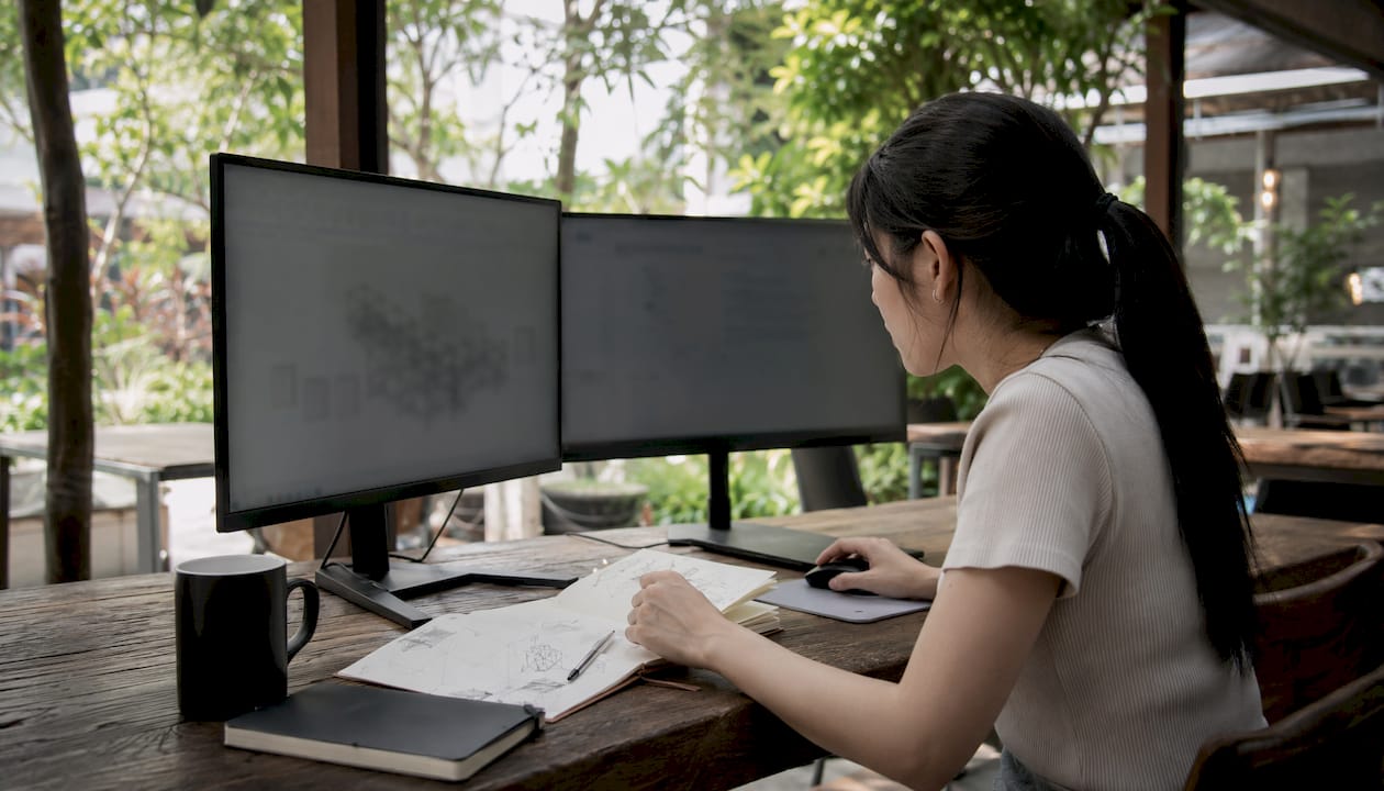 Engineer hands coordinating BIM workflow on dual monitors