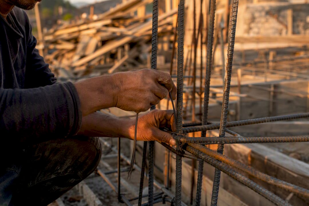 Three Design Strategies Prevent Structural Collapse Hands tying steel reinforcement bars on site