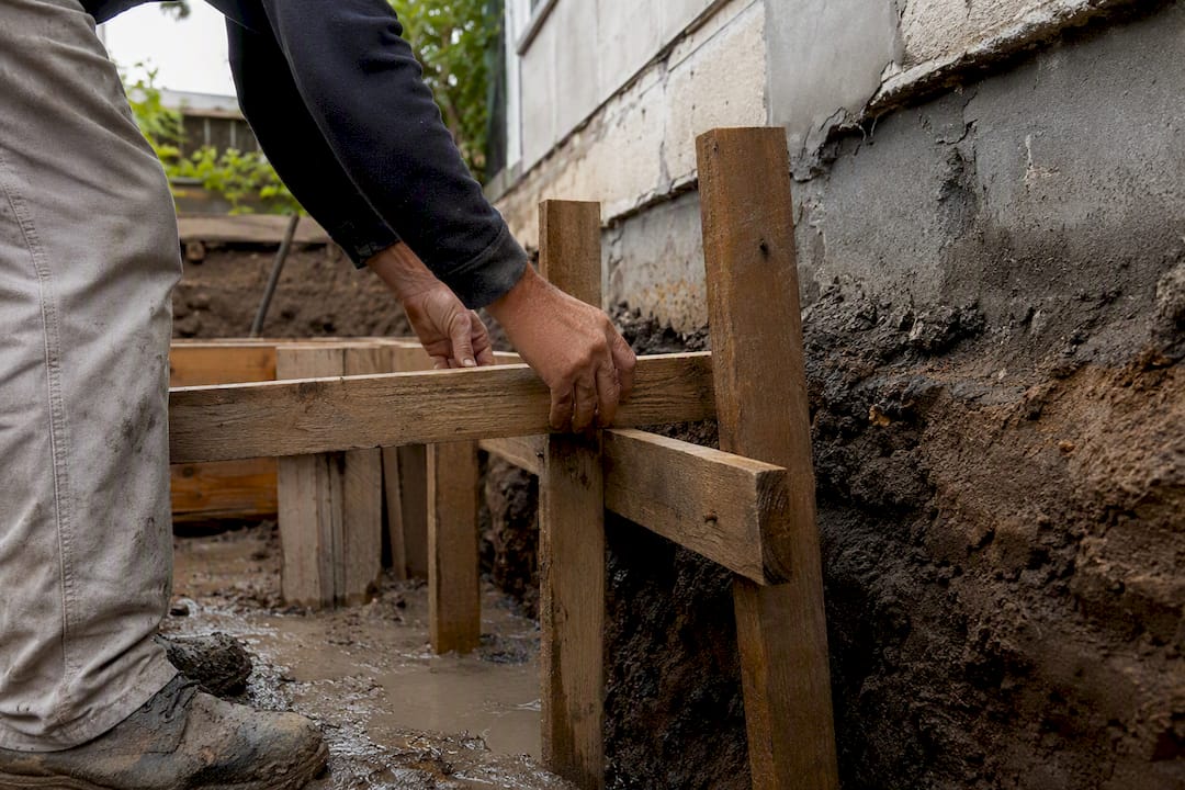 Worker installing shoring supports near boundary excavation