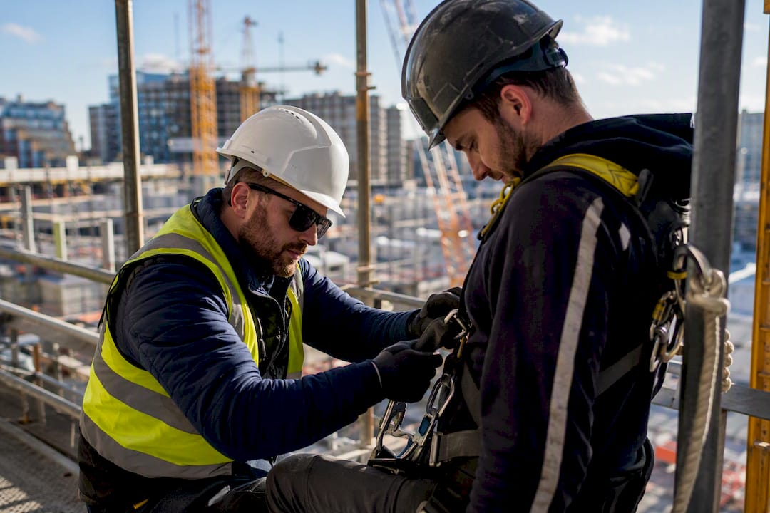 Supervisor adjusting worker's safety harness