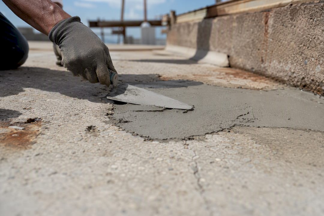 Spalling Concrete Repair: What Owners Need to Know Hand applying repair mortar on spalled concrete