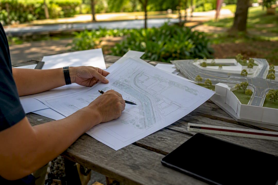 Hands arranging site plan and tools for LTA meeting