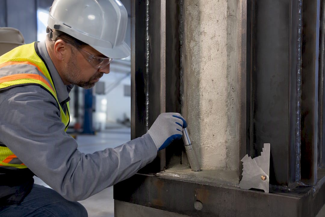 Engineers: Column Jacketing Methods With 25–49% Lab Capacity Gains Technician sampling grout beside steel column jacket