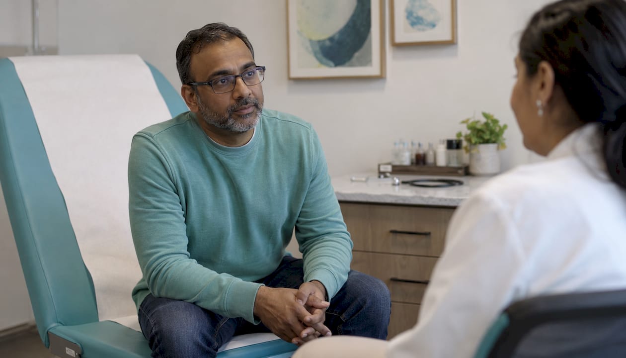 Man consulting doctor in medical exam room