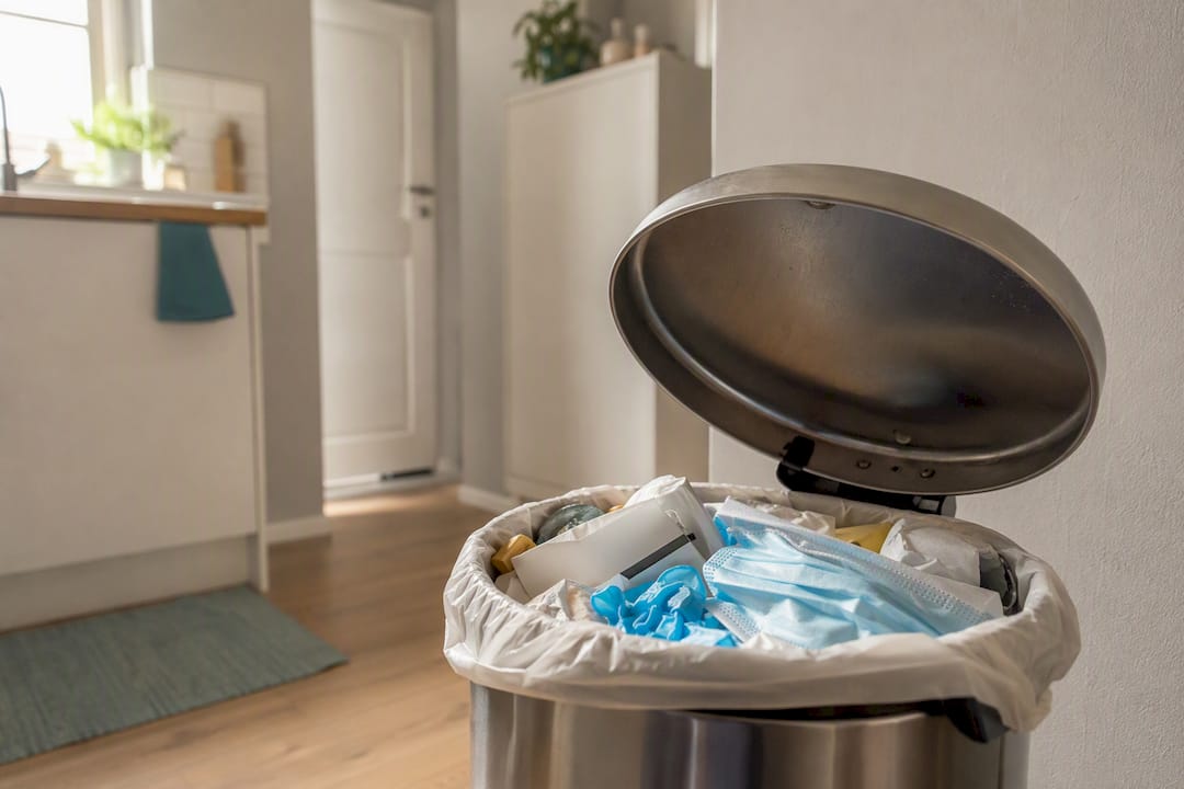 Waste bin with used test kit packaging and mask