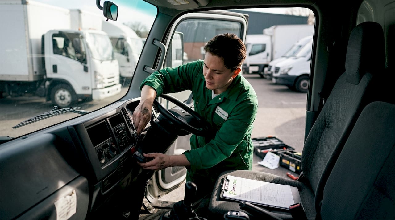 Mechanic installs telematics device in truck cab