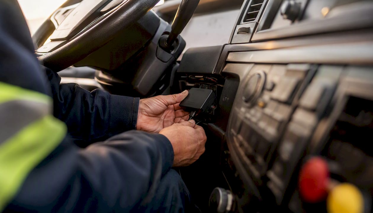 Technician installing telematics device in truck cab