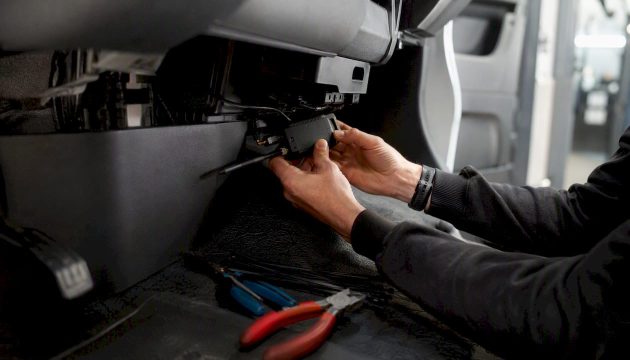 Hands installing telematics device in delivery van