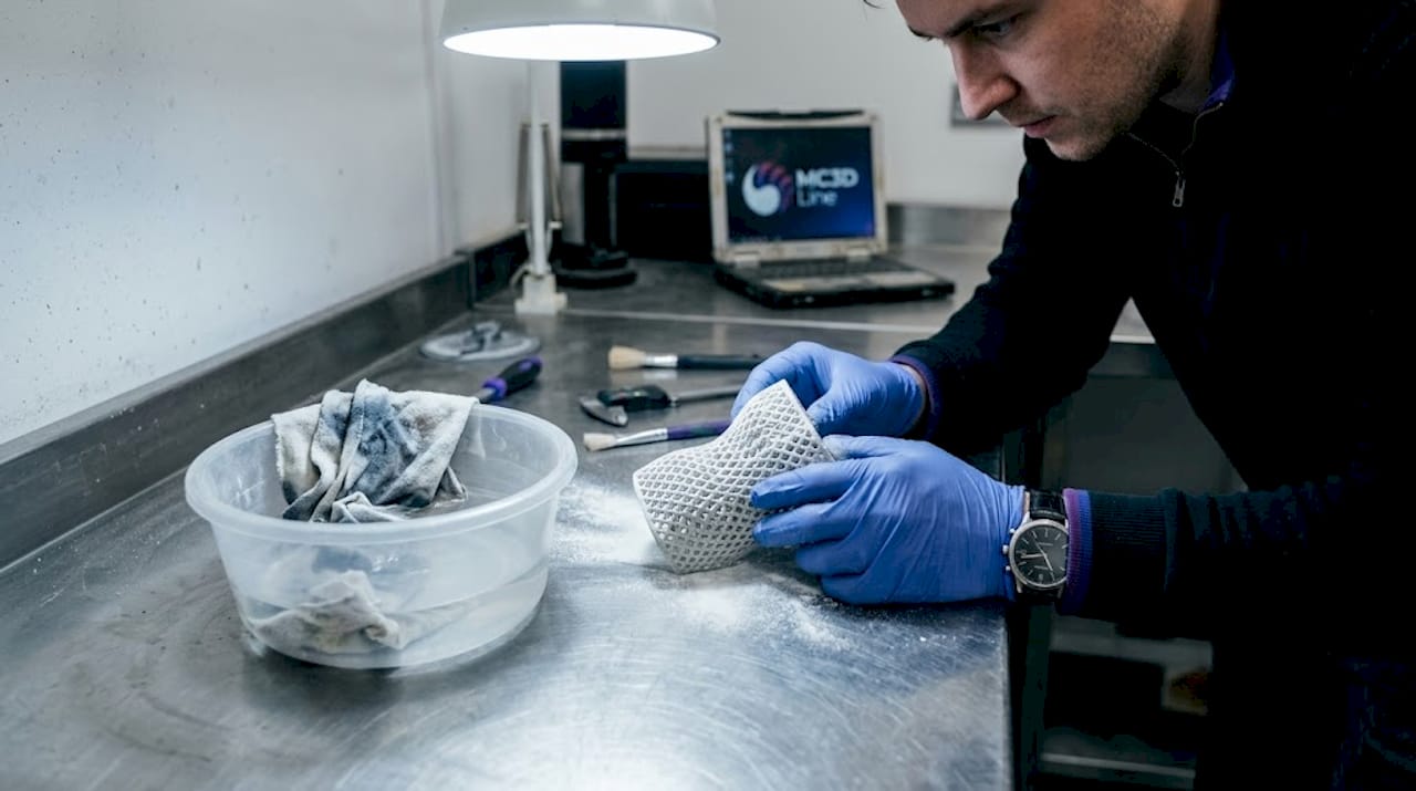 Un technicien vérifie la qualité du post-traitement d’une pièce imprimée en 3D.