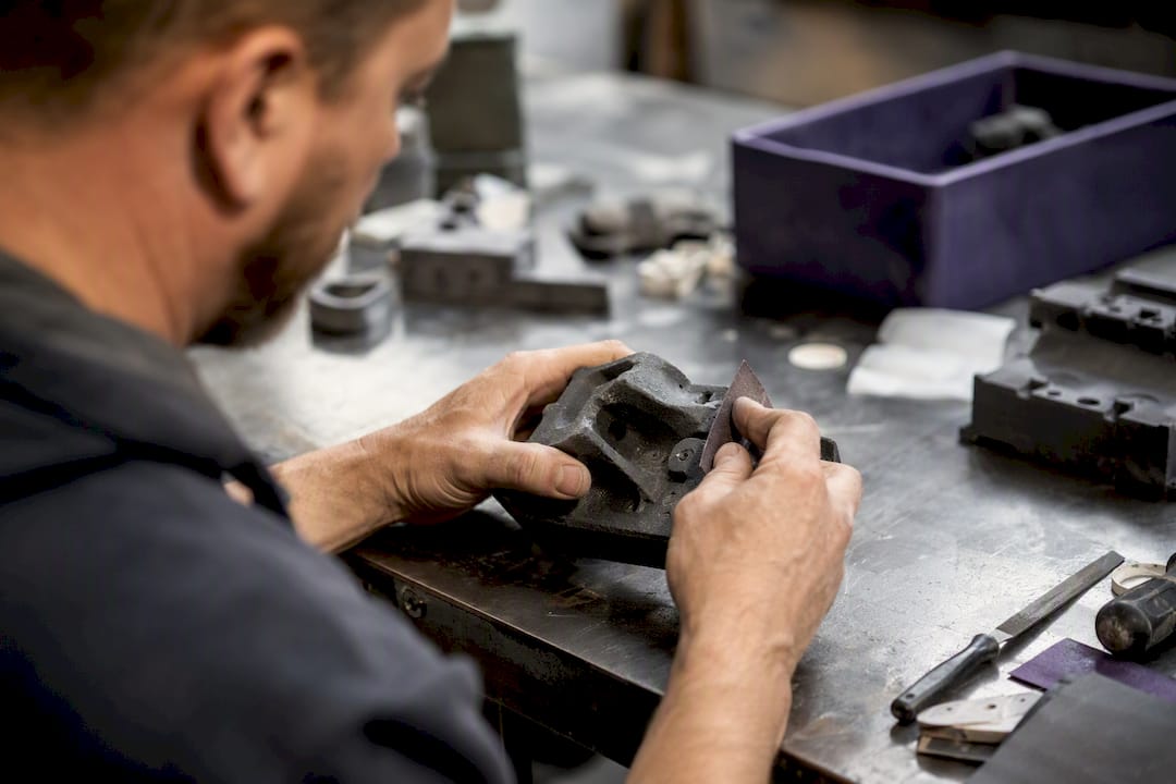 Mains ponçant une pièce imprimée en 3D par SLS