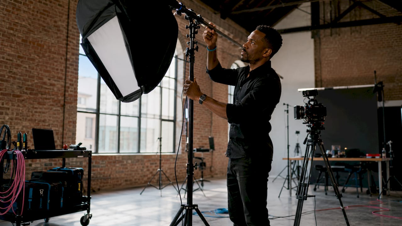 Videographer adjusting lighting equipment in studio.