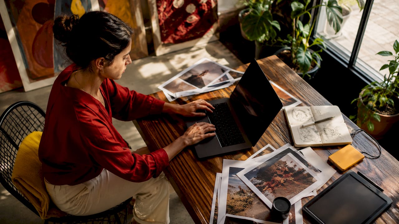 Woman editing images on laptop in sunny home office