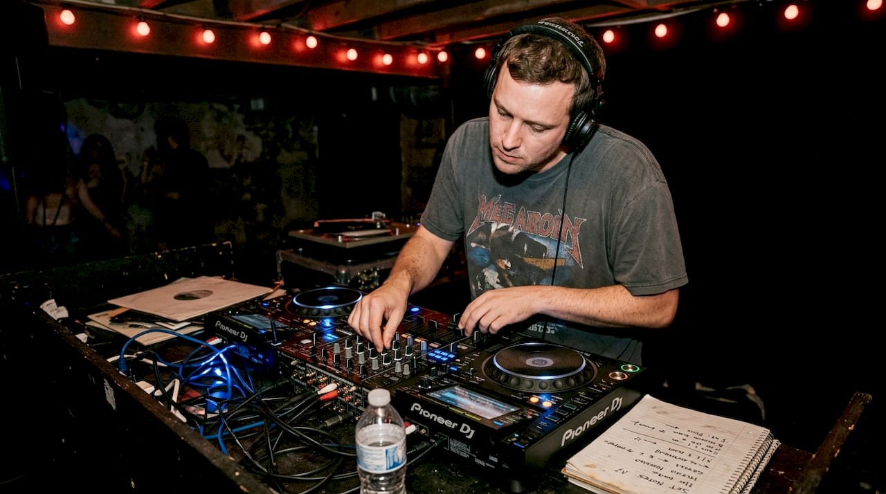 DJ mixing vinyl records in nightclub booth