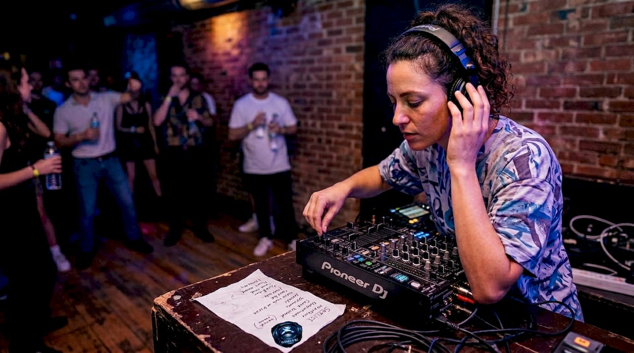 DJ mixing at busy underground club booth