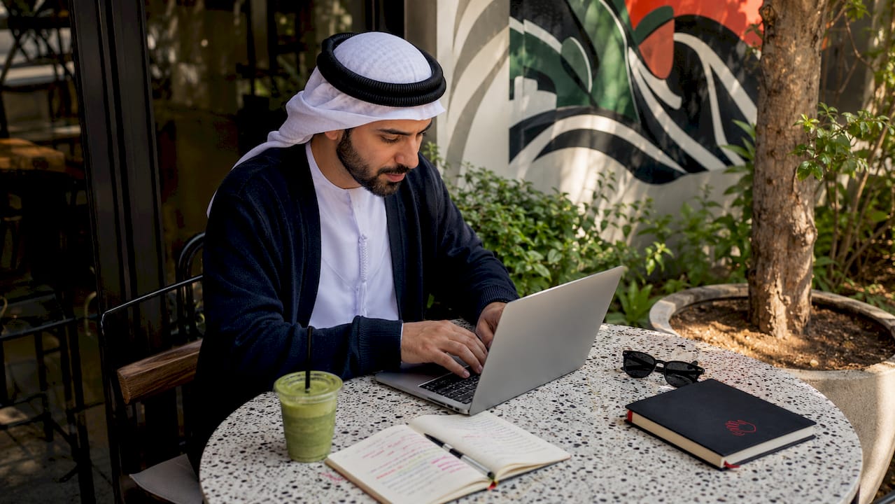 Hands typing SEO title tags on laptop in café
