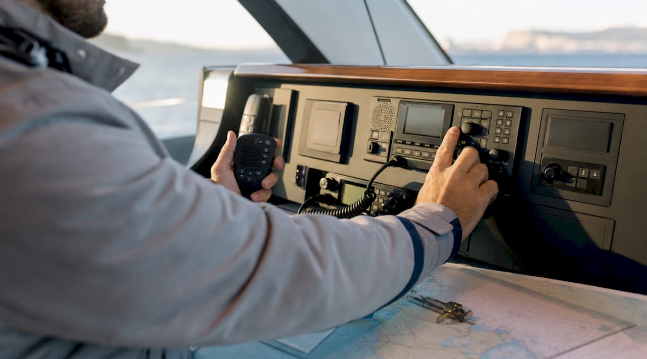 Hands operating DSC marine radio inside yacht cabin