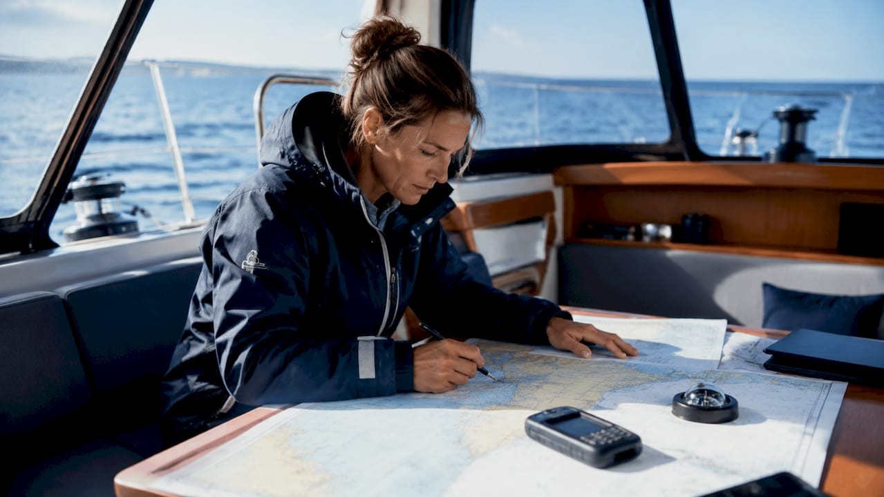 Solo sailor navigating with charts and GPS indoors