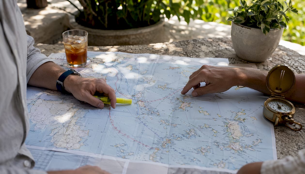 Hands pointing at Cyclades ferry routes on map