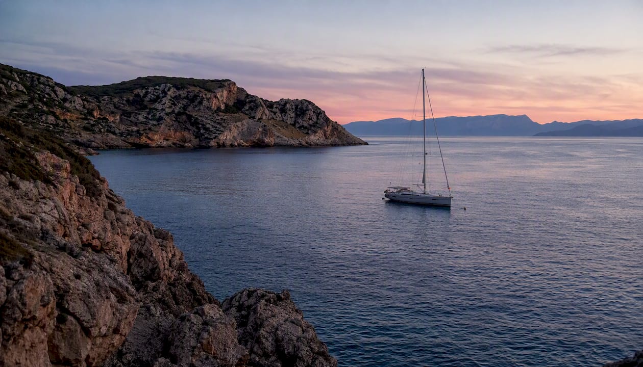 Sailing yacht moored in Mediterranean cove at sunset