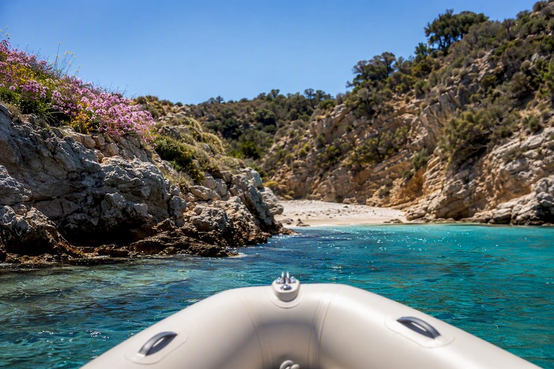 Dinghy approaching quiet rocky Mediterranean cove