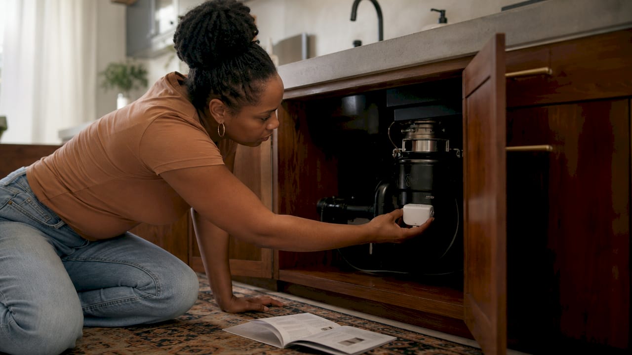 Homeowner installing smart leak detector under sink